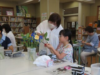 写真：枝を切る位置のアドバイスを受ける小学生